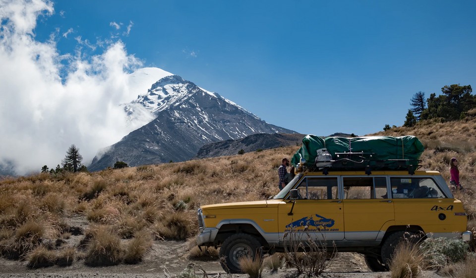 A car passes through with the Orizaba Peak in the background 