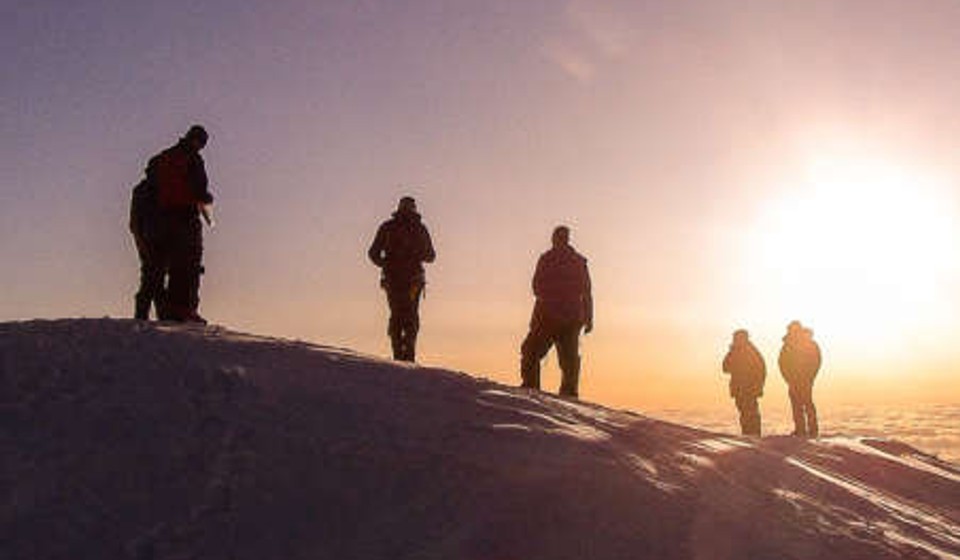 Mountainerrs climbing a mountain at sunrise