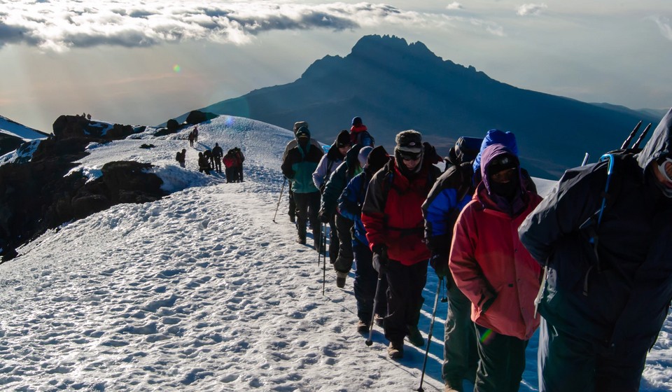 Final ascent to the top of Kilimanjaro or Uhuru Peak. A line of hikers stepping over snow. 