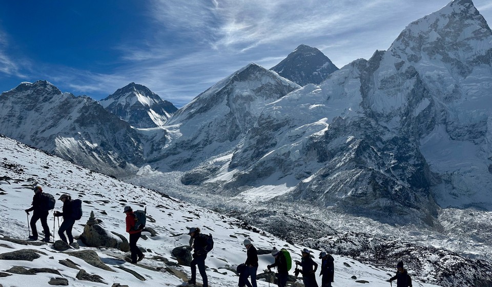 Trekkers trekking up a snow covered trail in the Himalayas