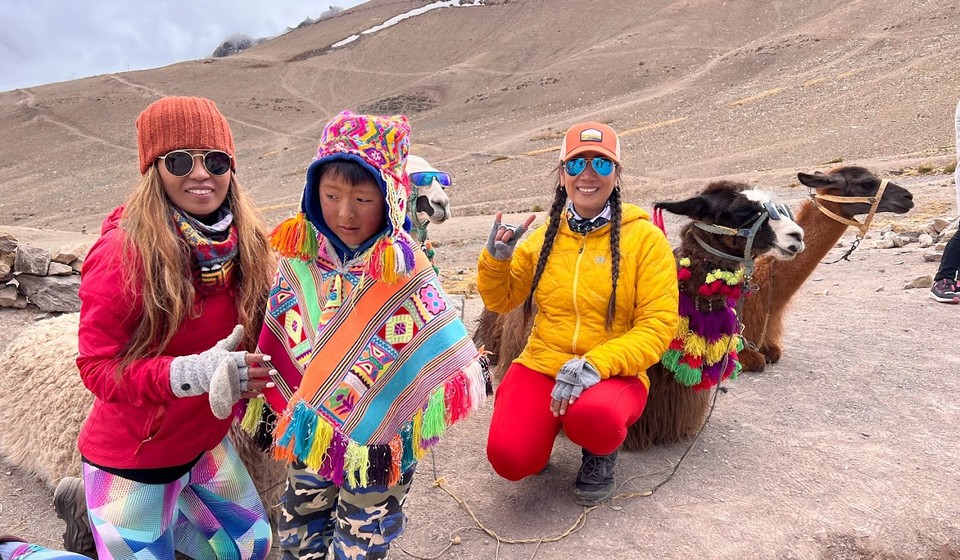 travelers posing with alpacas and a local boy dressed in traditional clothes